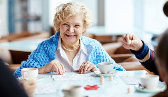An elderly woman smiling while she plays bingo